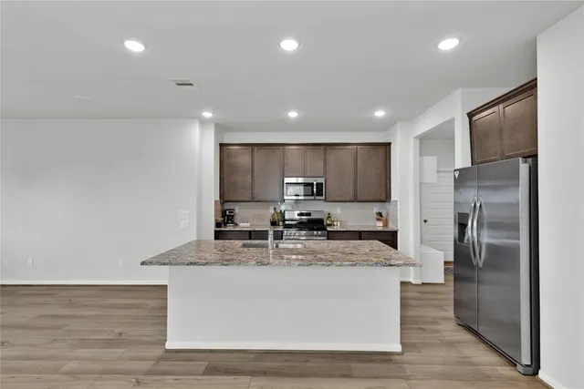 a large kitchen with stainless steel appliances granite countertop a sink a stove a refrigerator and a cabinets