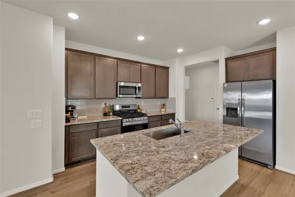 a kitchen with kitchen island granite countertop wooden cabinets and refrigerator