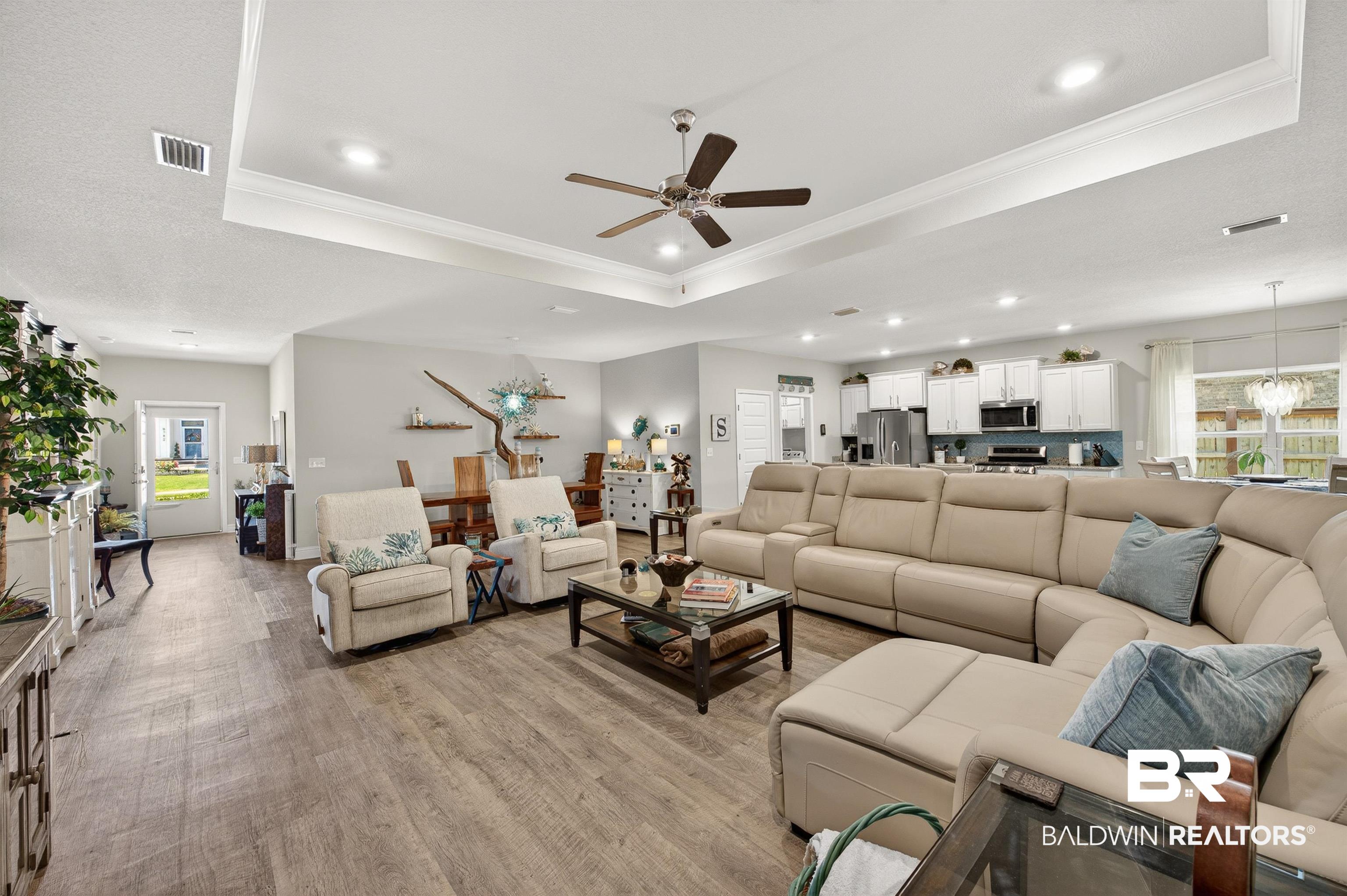 8735 Bronze Lane Foley, AL 36535 - Photo 2 of 58 Open-concept living space featuring wood-finish flooring, a tray ceiling with recessed lighting, and a ceiling fan