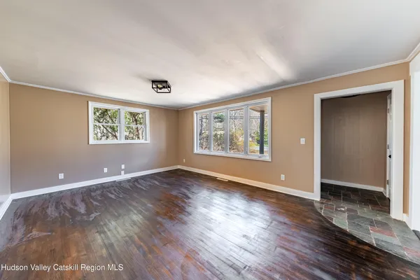 an empty room with wooden floor and windows