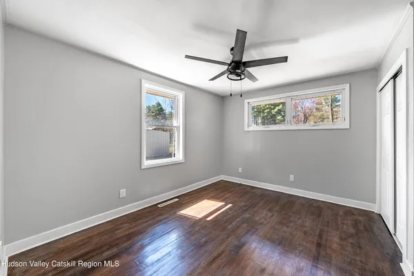 a view of empty room with wooden floor and fan