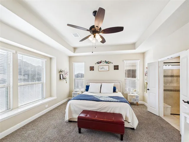 a bedroom with a large bed and a chandelier fan