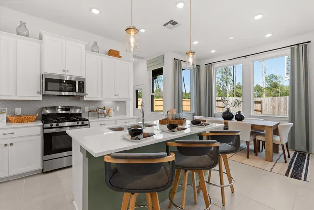 a kitchen with stainless steel appliances granite countertop a stove a sink a microwave a dining table and chairs