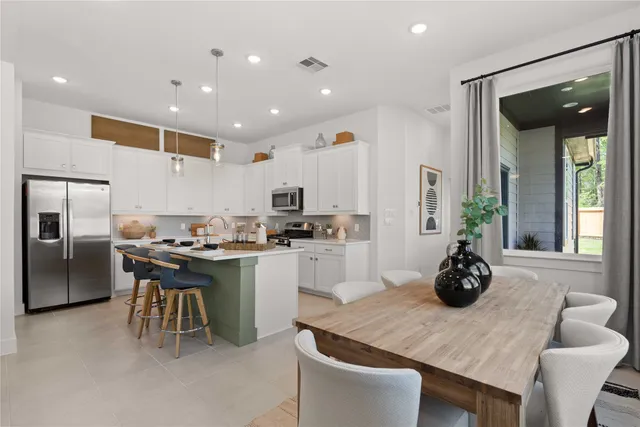 a kitchen with stainless steel appliances granite countertop a sink a stove a refrigerator and chairs