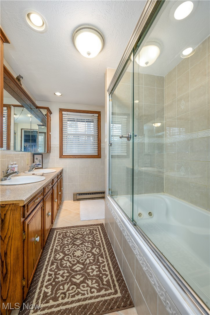 17080 Heiser Road Berlin Center, OH 44401 - Photo 33 of 35 Bathroom featuring a baseboard radiator, enclosed tub / shower combo, tile patterned floors, a textured ceiling, and vanity