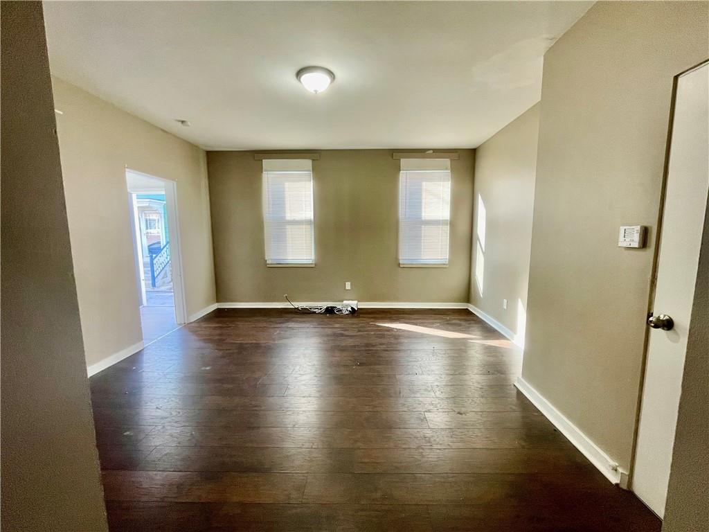1104 Brabec Street Pittsburgh, PA 15212 - Photo 5 of 26 an empty room with wooden floor and windows with curtains