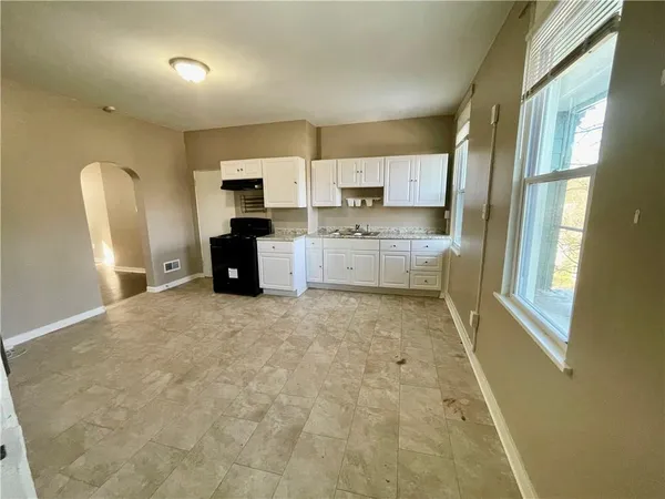 a large white kitchen with sink refrigerator and window