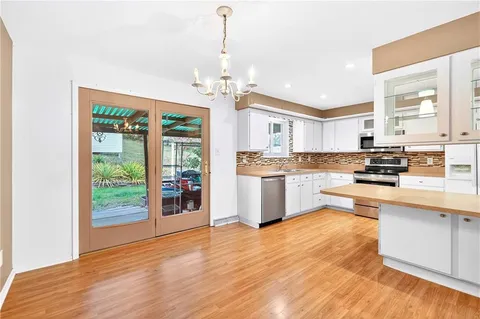 a kitchen with stainless steel appliances granite countertop a refrigerator a oven a stove and a wooden floors