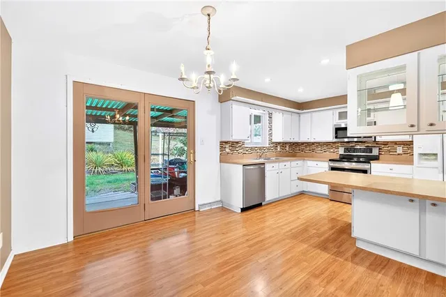 a kitchen with stainless steel appliances granite countertop a refrigerator a oven a stove and a wooden floors