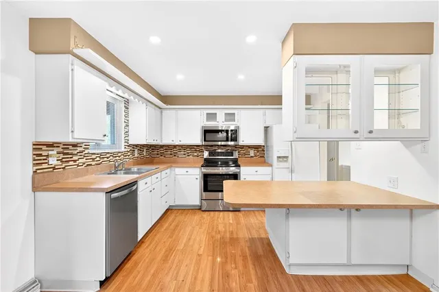 a kitchen with stainless steel appliances granite countertop a stove a sink and white cabinets with wooden floor