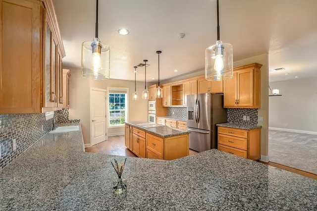 a large kitchen with granite countertop a large counter top stainless steel appliances and wooden floor