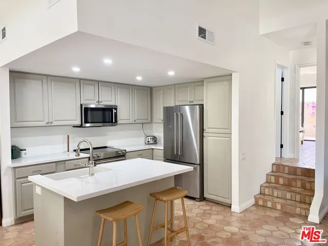 a kitchen with stainless steel appliances a sink a stove a refrigerator cabinets and a dining table