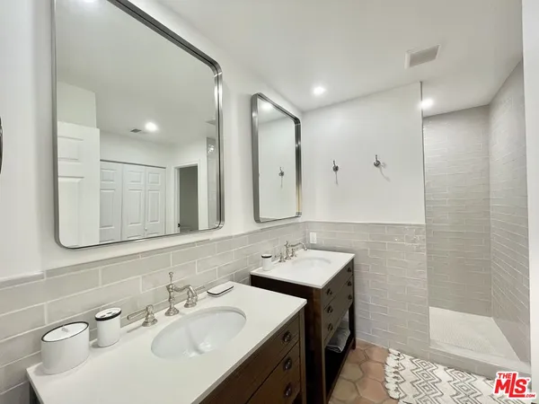 a bathroom with a double vanity sink mirror and shower