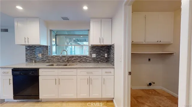 a sink with granite countertop white cabinets and a sink