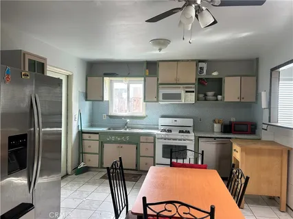 a kitchen with stainless steel appliances granite countertop a sink a stove a refrigerator cabinets and chairs