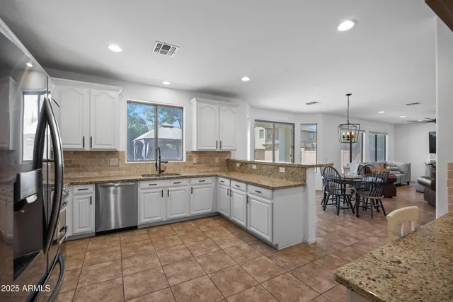 a kitchen with granite countertop a refrigerator and a stove top oven