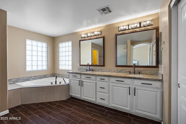 a large spacious bathroom with a granite countertop tub a sink and a large mirror