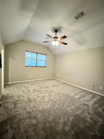 an empty room with a ceiling fan and window