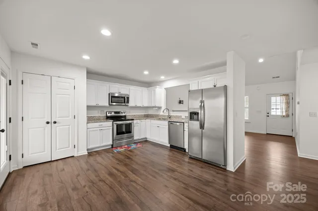 a large kitchen with stainless steel appliances granite countertop a refrigerator and a sink