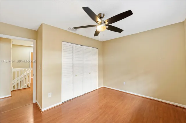 an empty room with wooden floor fan and windows
