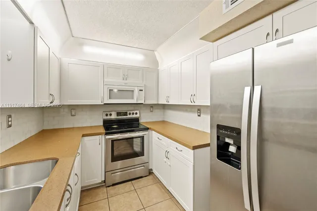 a kitchen with stainless steel appliances granite countertop a refrigerator a stove and white cabinets