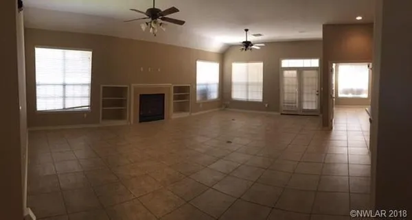 a view of an empty room with a fireplace and a window