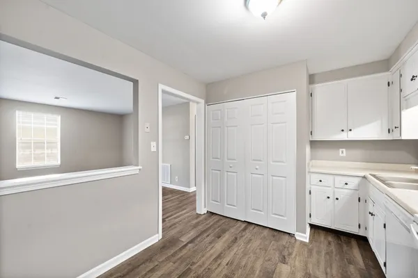 a view of a kitchen with white cabinets and wooden floor