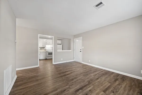 a view of a room with wooden floor kitchen view and a window