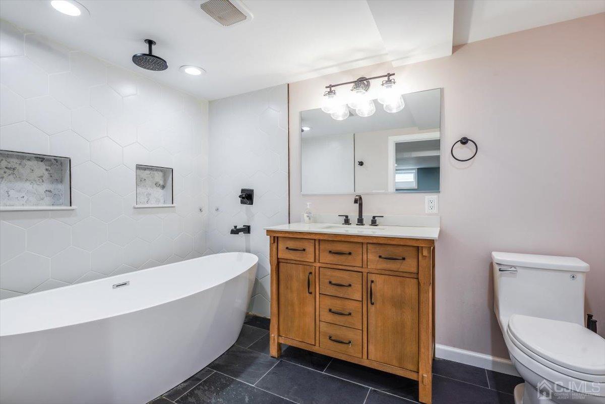 364 New Market Road Dunellen, NJ 08812 - Photo 2 of 36 a spacious bathroom with a granite countertop toilet a sink a mirror and a bathtub