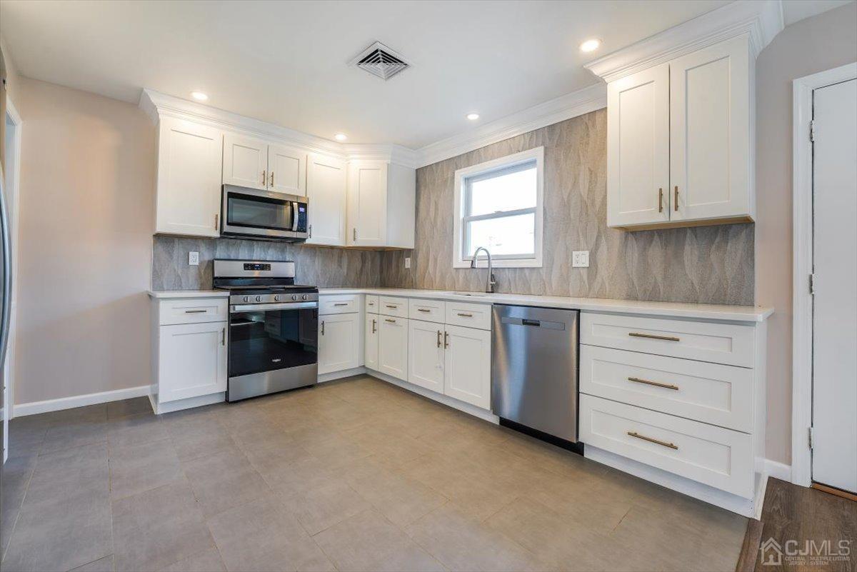 364 New Market Road Dunellen, NJ 08812 - Photo 21 of 36 a kitchen with white cabinets stainless steel appliances and window