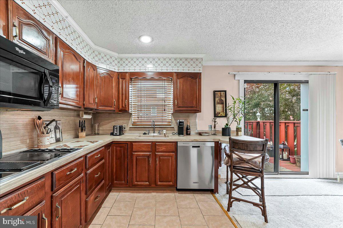 8309 Lynnewood Road Philadelphia, PA 19150 - Photo 9 of 28 a kitchen with stainless steel appliances granite countertop wooden cabinets a sink dishwasher a stove and a refrigerator with wooden floor