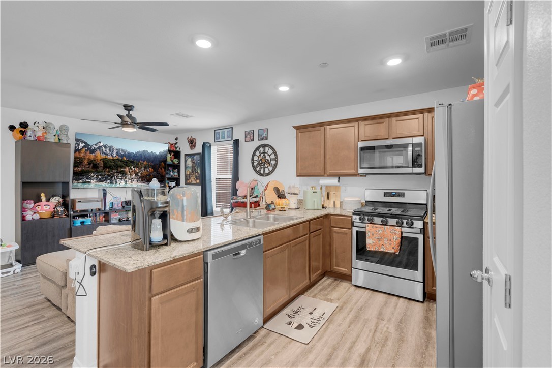 4536 Woolcomber Street Las Vegas, NV 89115 - Photo 17 of 34 Kitchen featuring a peninsula, stainless steel appliances, light stone counters, light wood finished floors, and recessed lighting