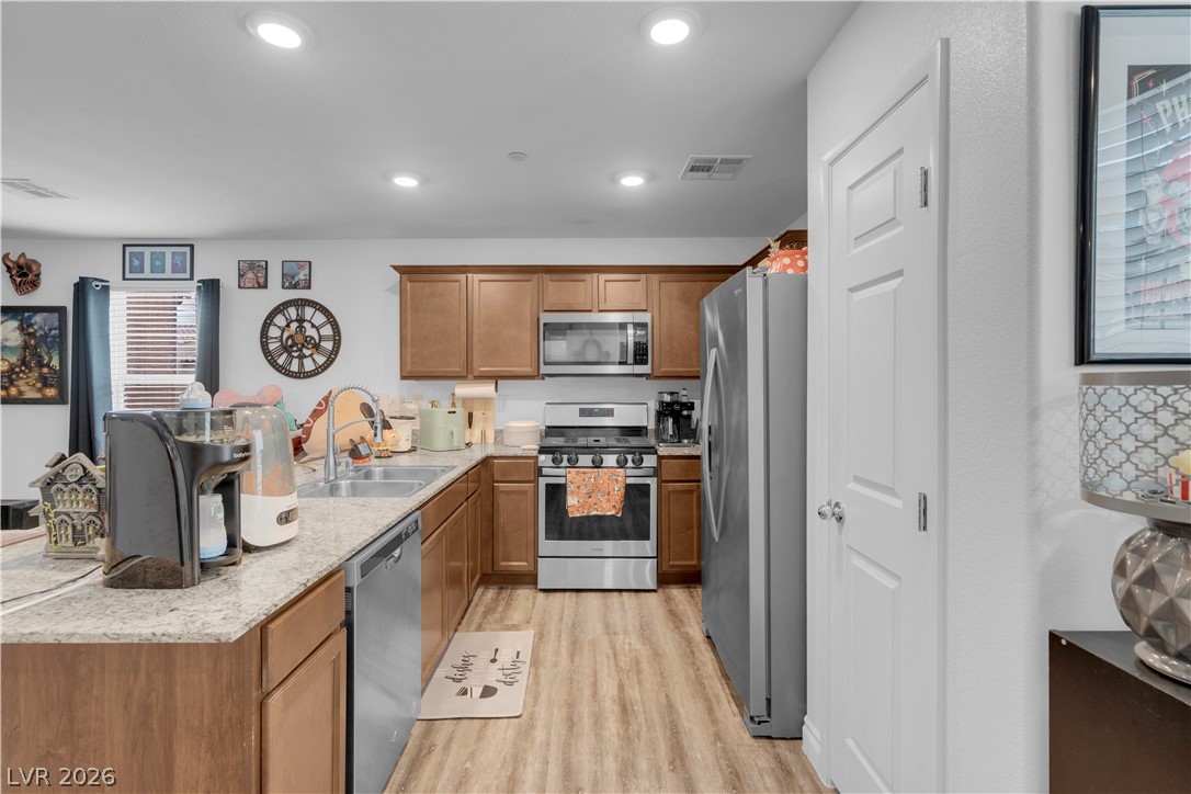 4536 Woolcomber Street Las Vegas, NV 89115 - Photo 18 of 34 Kitchen with wood finish cabinetry, stainless steel appliances, a peninsula, light wood-type flooring, and recessed lighting