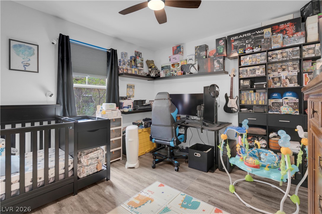 4536 Woolcomber Street Las Vegas, NV 89115 - Photo 24 of 34 Bedroom with an office area, light wood-type flooring, a crib, and a ceiling fan