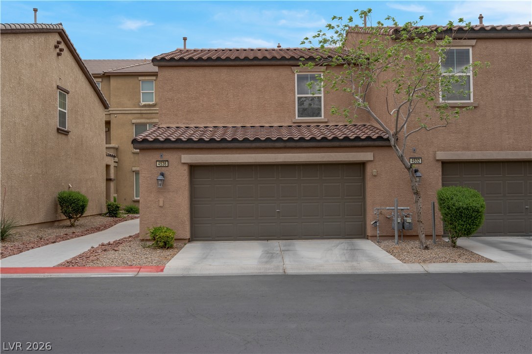 4536 Woolcomber Street Las Vegas, NV 89115 - Photo 4 of 34 Mediterranean / spanish home with stucco siding, a garage, a tiled roof, and driveway