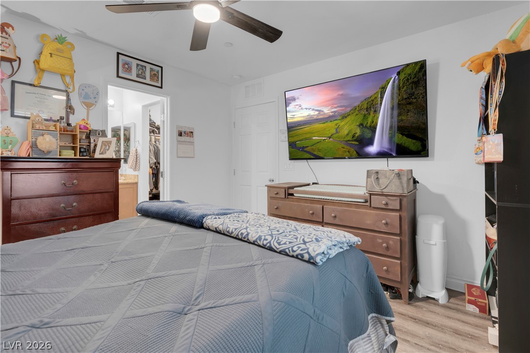 4536 Woolcomber Street Las Vegas, NV 89115 - Photo 10 of 34 Bedroom featuring a spacious closet, a ceiling fan, and light wood-type flooring
