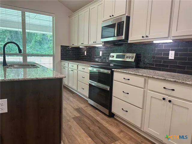 a kitchen with granite countertop white cabinets and a stove