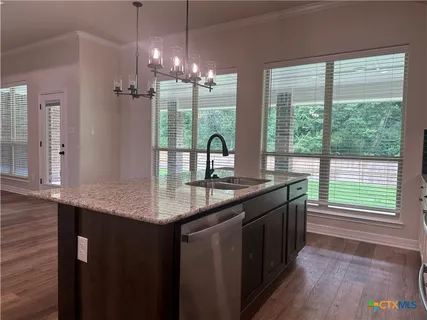 a kitchen with kitchen island granite countertop a sink a counter top space and stainless steel appliances