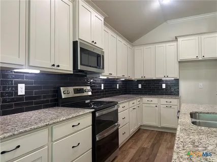 a kitchen with granite countertop white cabinets and white appliances
