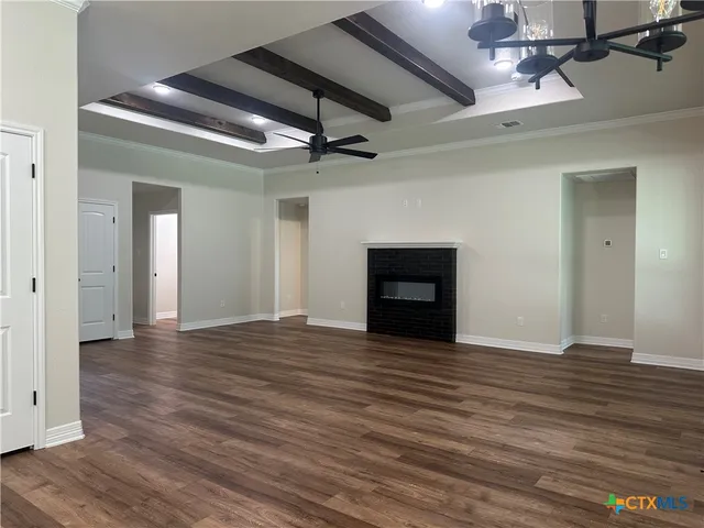 a view of an empty room with wooden floor a fireplace and a window