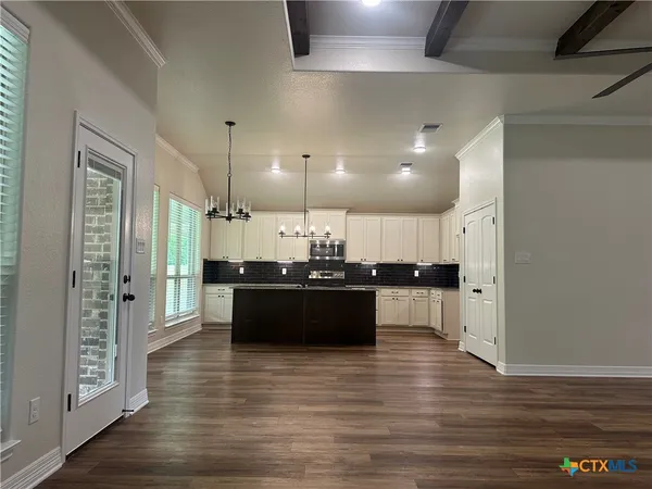 a large kitchen that has a lot of cabinets and wooden floor