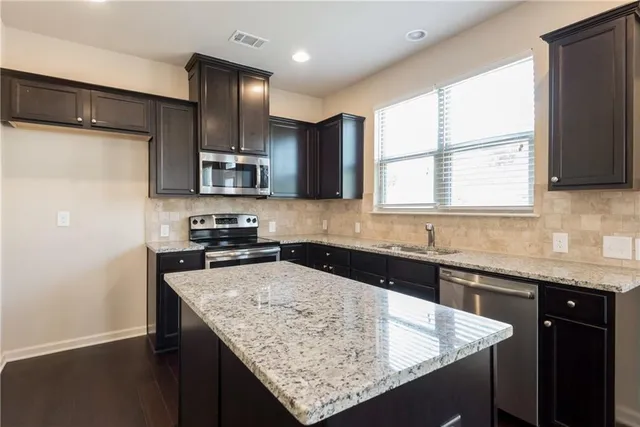 a kitchen with granite countertop stainless steel appliances a sink stove top oven and granite counter tops