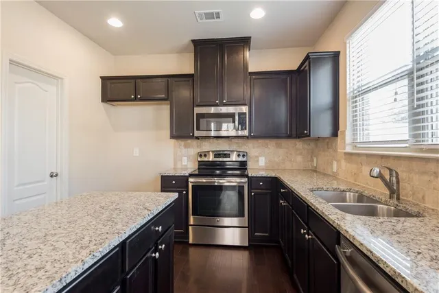 a kitchen with stainless steel appliances granite countertop a sink stove and oven