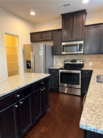 a kitchen with stainless steel appliances granite countertop a stove a sink dishwasher a refrigerator and a microwave