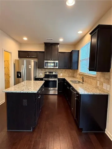 a large kitchen with stainless steel appliances wooden cabinets a stove and a refrigerator