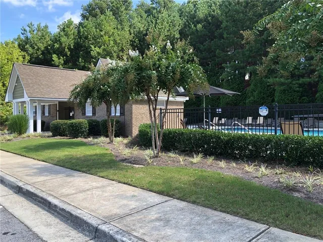 a view of a house with a yard and large trees