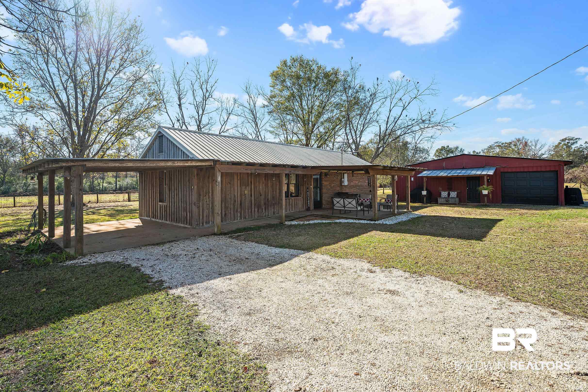 View of front of house with an outbuilding, a front yard, driveway, an attached carport, and a metal roof