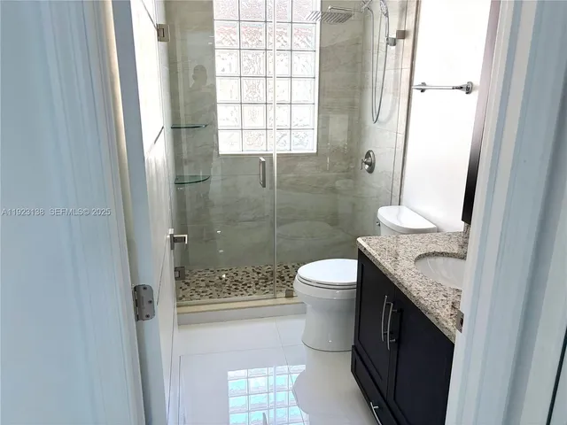 a bathroom with a granite countertop sink a toilet a mirror and shower