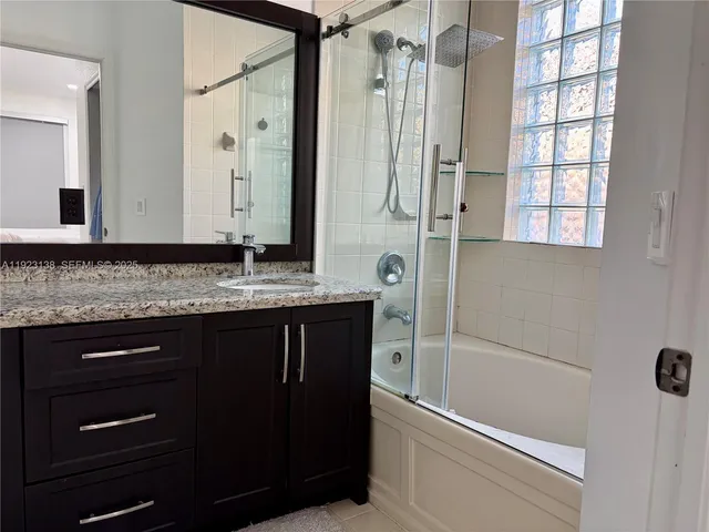 a bathroom with a granite countertop sink a mirror and a bathtub