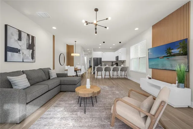 a living room with furniture kitchen view and a chandelier